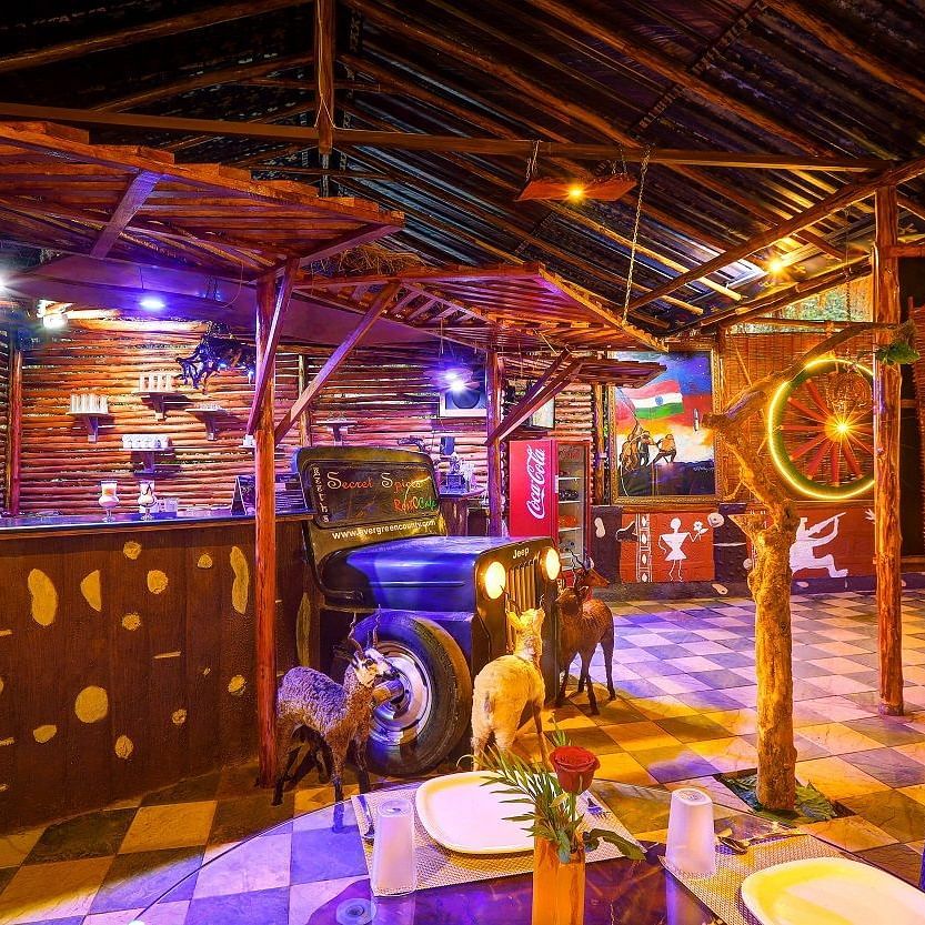 Quirky restaurant interior with vibrant lighting, vintage decor, and a jeep repurposed as a bar counter - Evergreen County