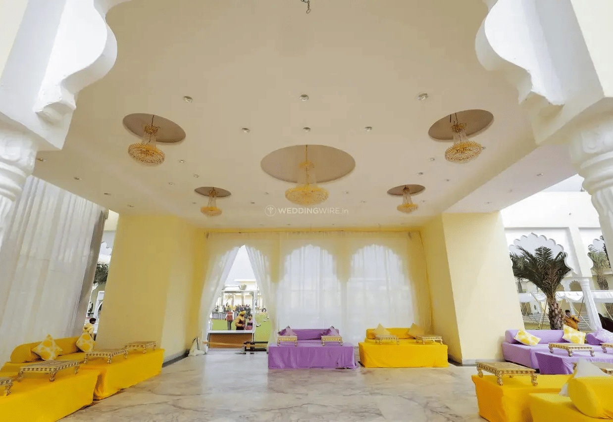 Indoor hall with ceiling decor, long seating arrangement, and tables at Beelwa Palace, Jaipur