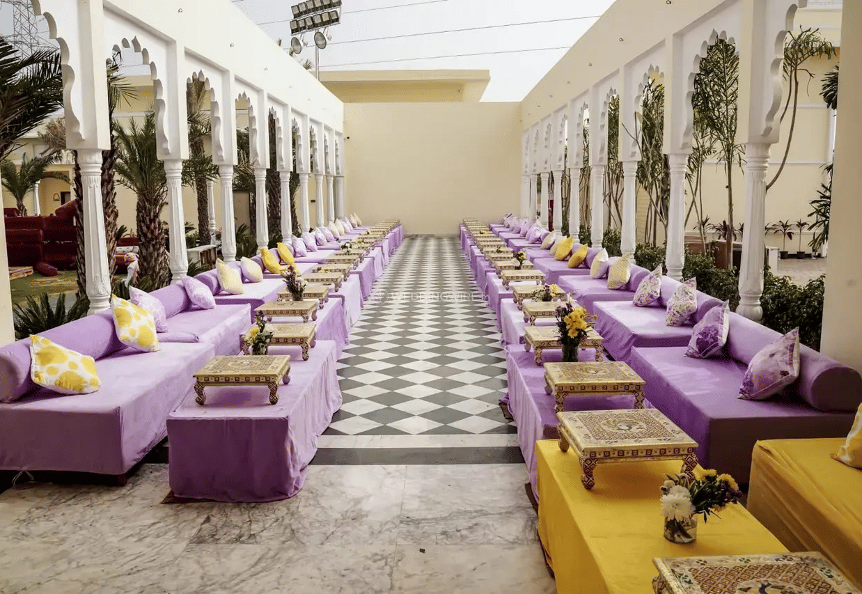 Long seating arrangement with low sofas and cushions lined along pillars at Beelwa Palace, Jaipur