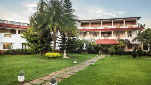 Lawn with red-roofed resort building in the background at a Yelagiri resort