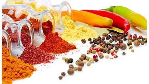 Array of colourful spices and a traditional dish placed on a vibrant table setting.