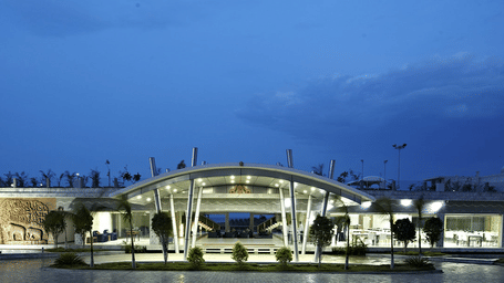The entrance of Grande Bay Resort & Spa, Mamallapuram, illuminated with bright lights, with the dining area on the right and a view of Arjuna’s Penance on the left.