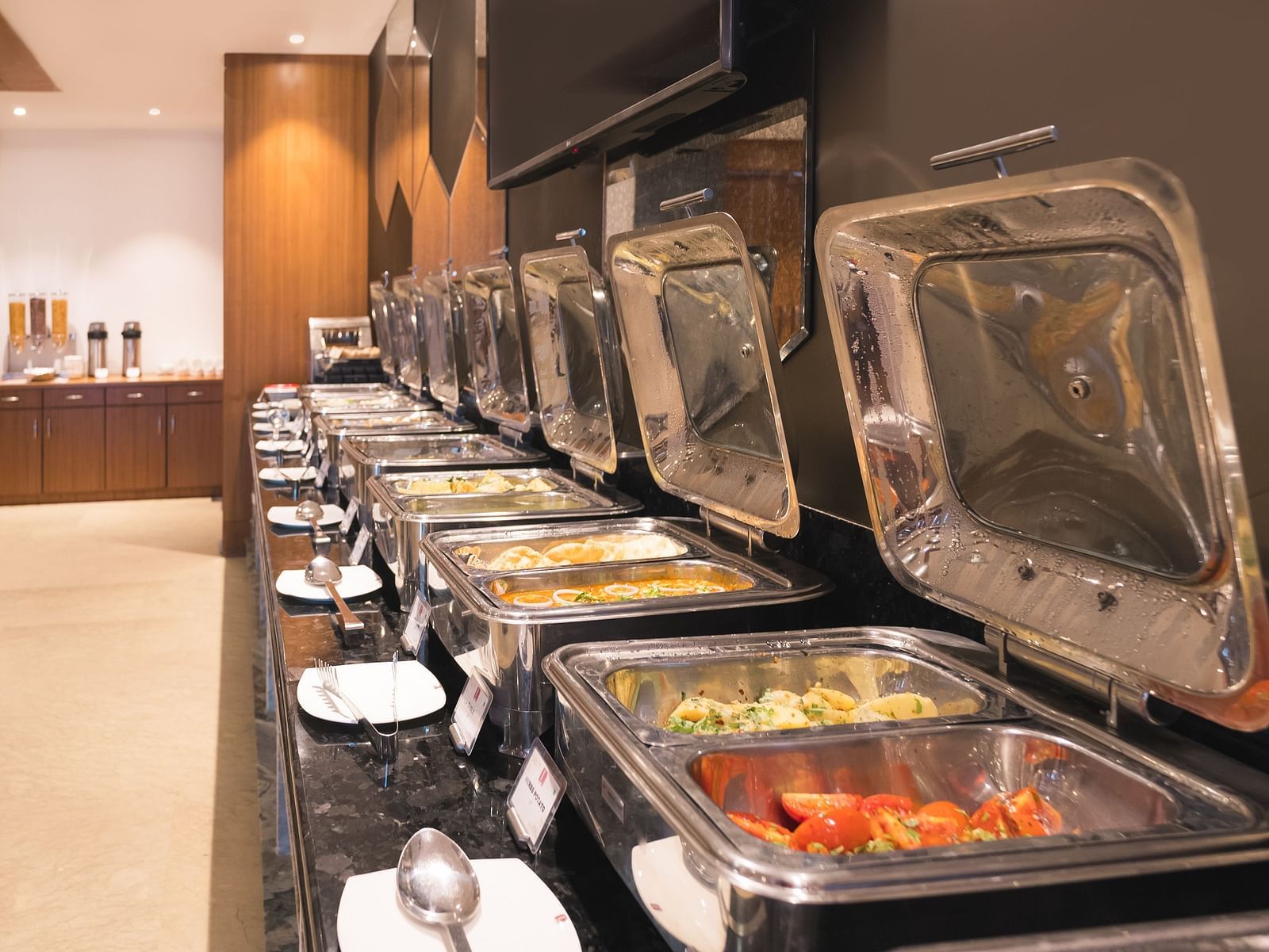 A buffet line at Lords Inn Udaipur displays various covered food warmers on a black countertop, ready for service.