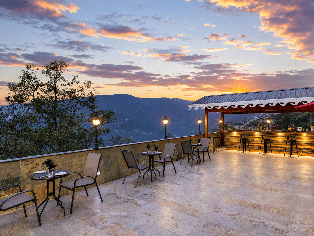 Terrace bar at Valmere Himalayan Hotel & Spa, Gangtok at sunset, with 3 wooden barstools, patio seating, red umbrellas, and mountain views beyond the railing.