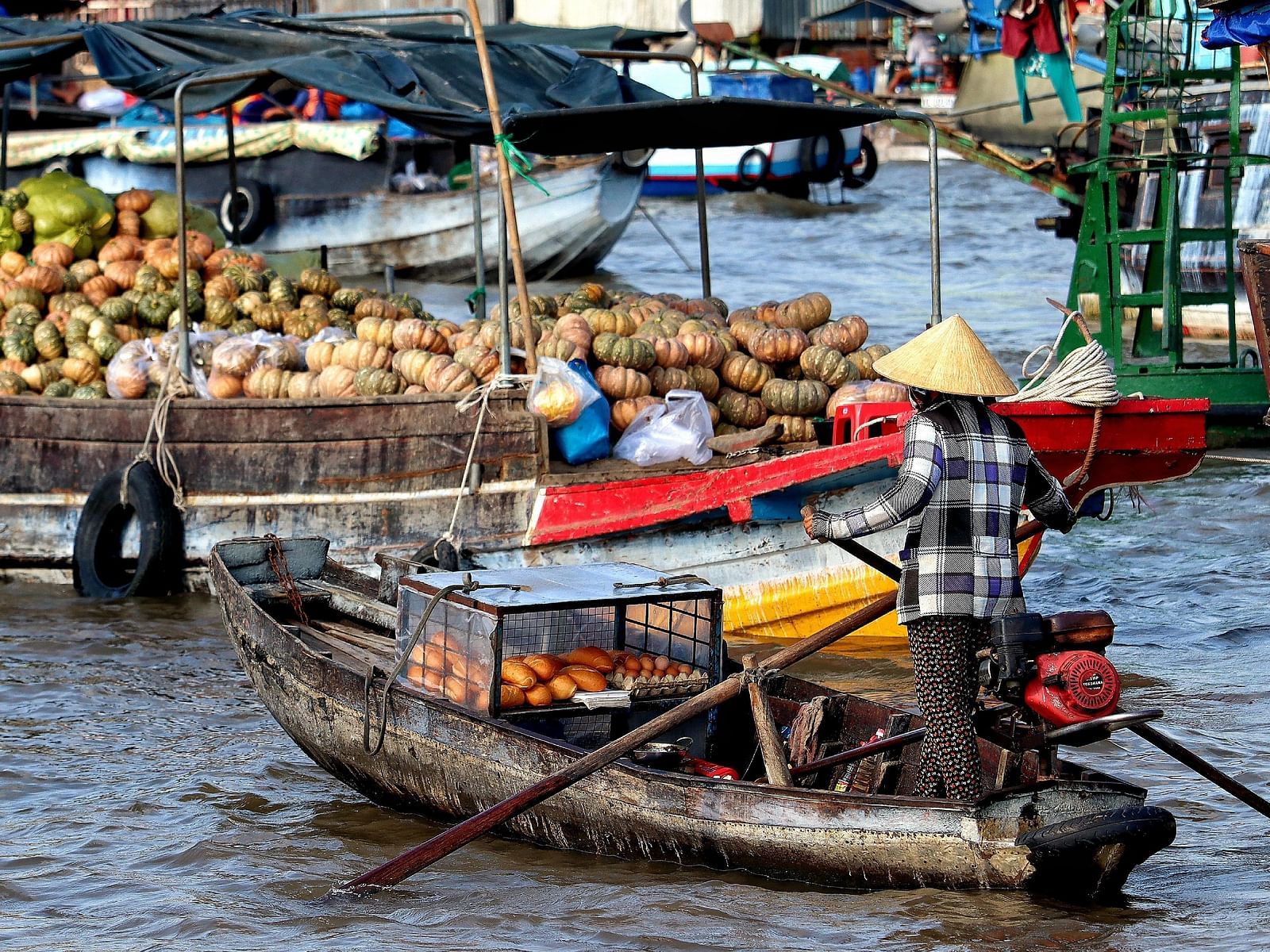 An overview of a floating market in the Mekong River with people on boats selling many items.