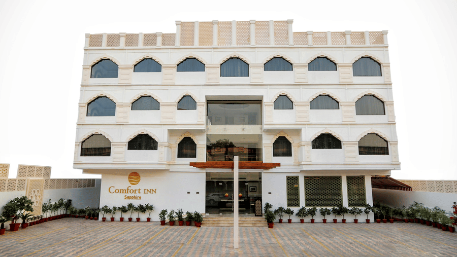 The exterior of Comfort Inn Sapphire by Eastlynn Collections, Jaipur showing building facade, balconies, entrance area, and open driveway.