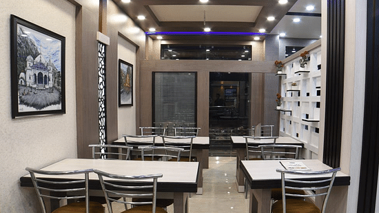 Restaurant with white tables and chairs at Hotel Panchvati Inn 2