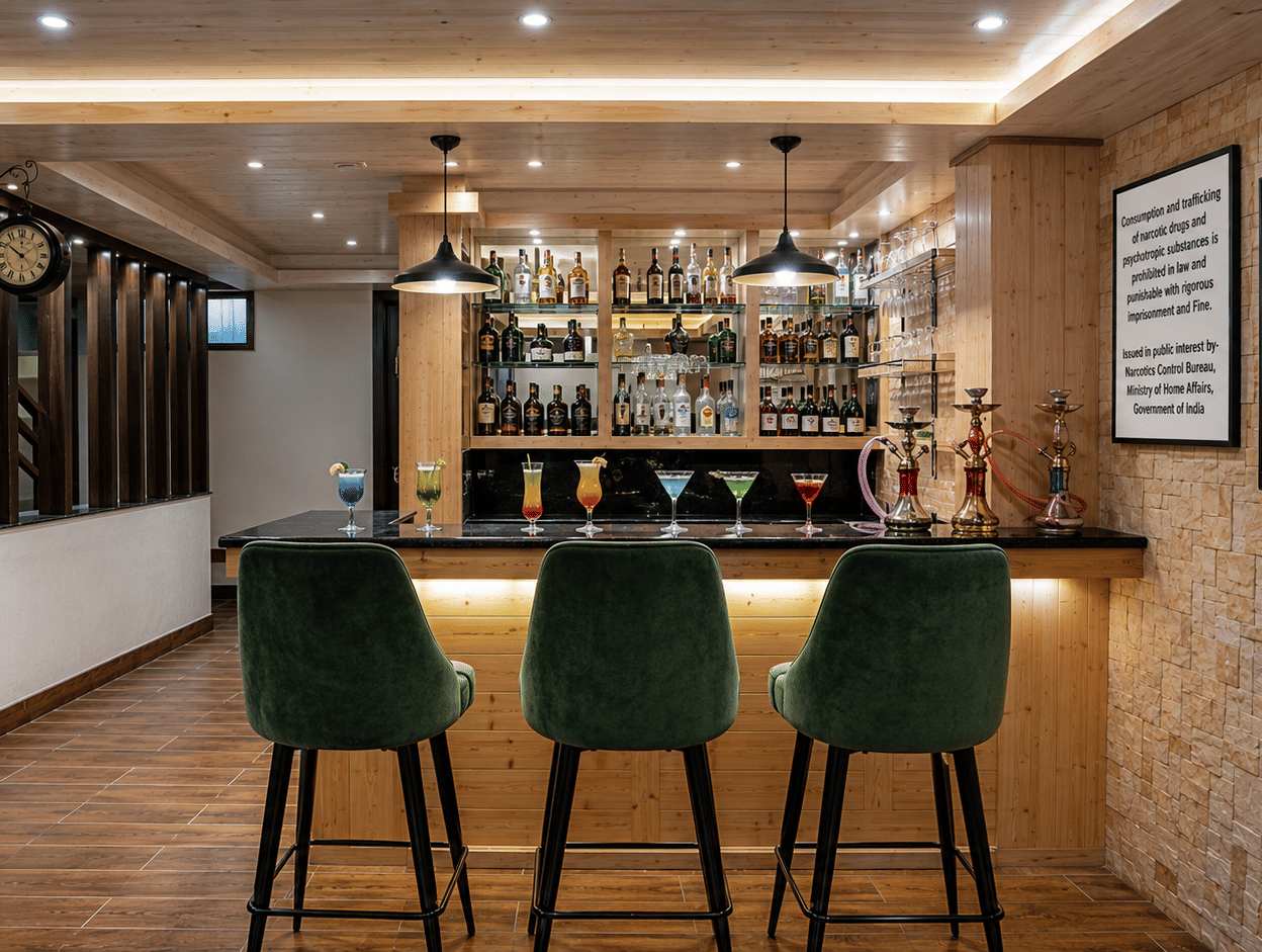 Bar counter at Valmere Magnolia Boutique Hotel & Spa, Pelling with 3 green velvet stools, backlit liquor shelves, colourful cocktails, and hookah pipes.