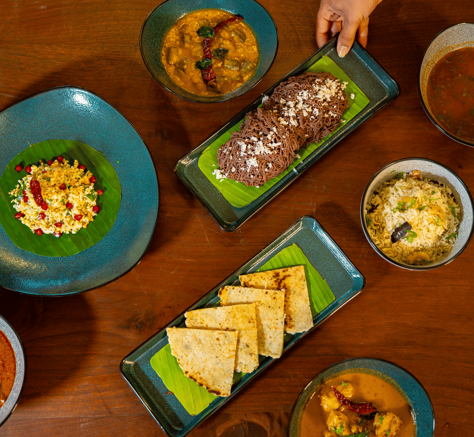 An overhead shot of a dining table at Stanley Revelation, filled with various plates of food on a wooden surface.