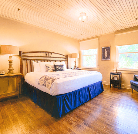 full view image of a room featuring a double bed with bed side tables along with a wooden cabinet in front of it - Historic Tapoco Lodge