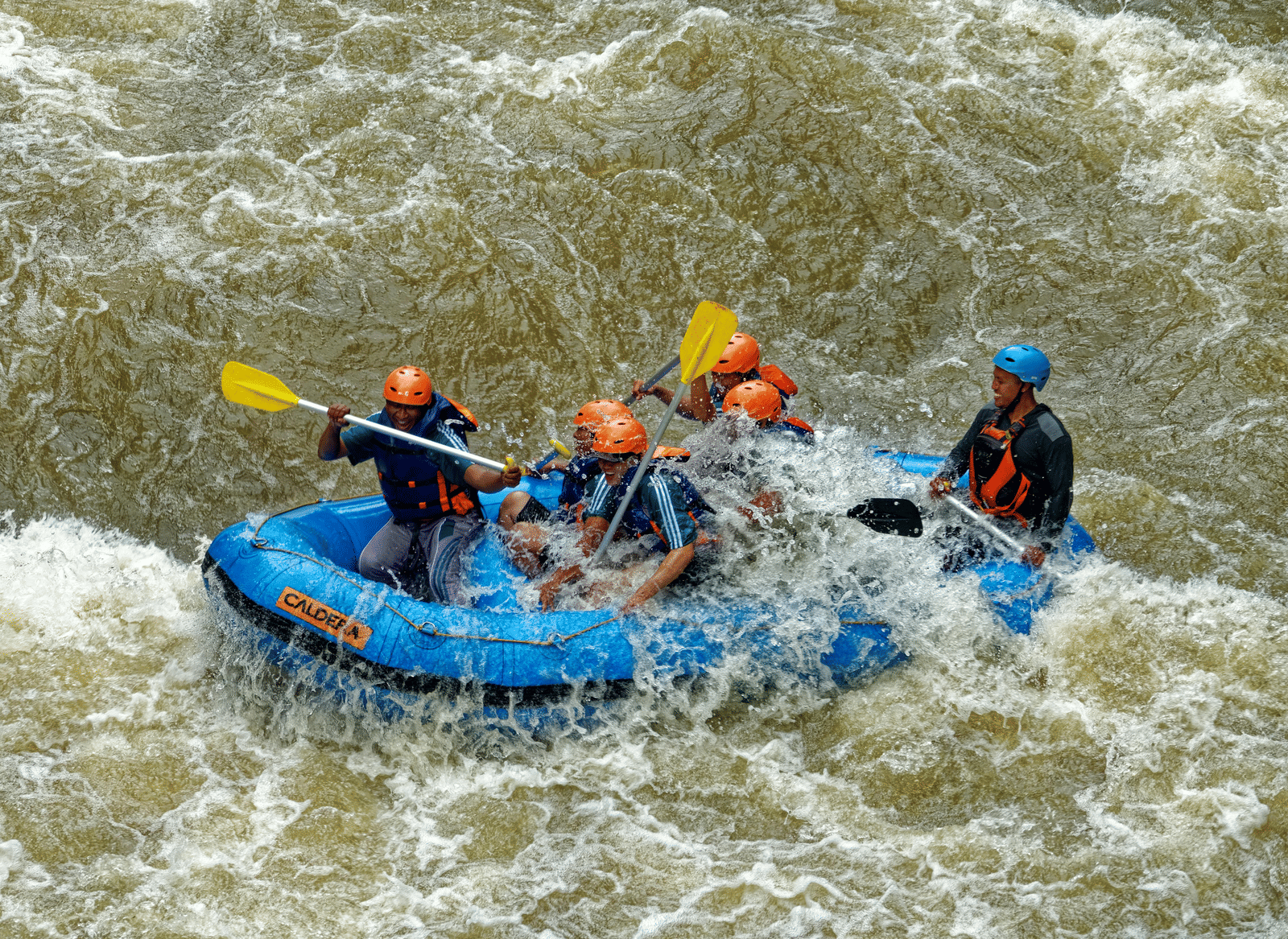 People in a raft navigate through choppy water.