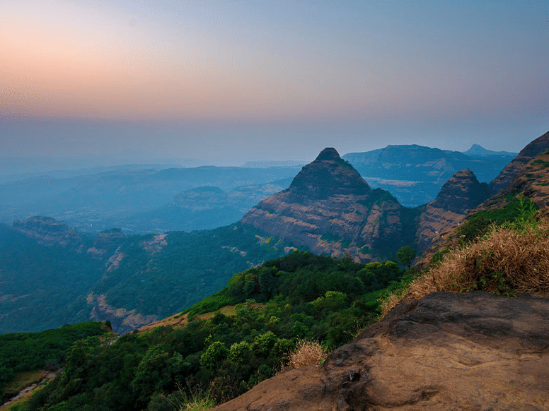 A landscape of a hilly elevation featuring hills in the horizon during the dusk