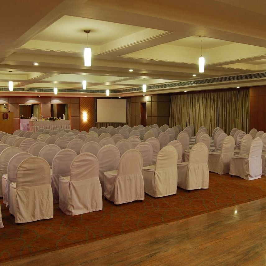 A well-lit banquet hall of Lords Plaza Ankleshwar with theatre style seating and elegant interiors creating a warm ambience