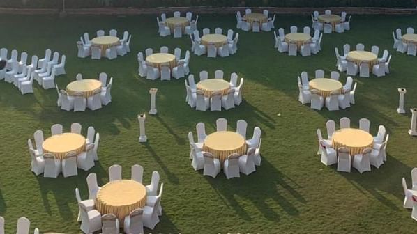 Outdoor banquet arrangement with round tables and chairs set on the lawn for a reception at Ilara Hotels & Spa, OMR, Chennai