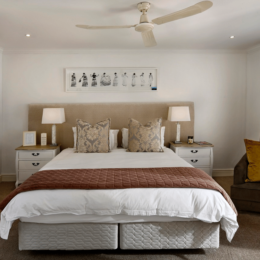 A king size bed with a ceiling fan hanging over it in a bedroom. 