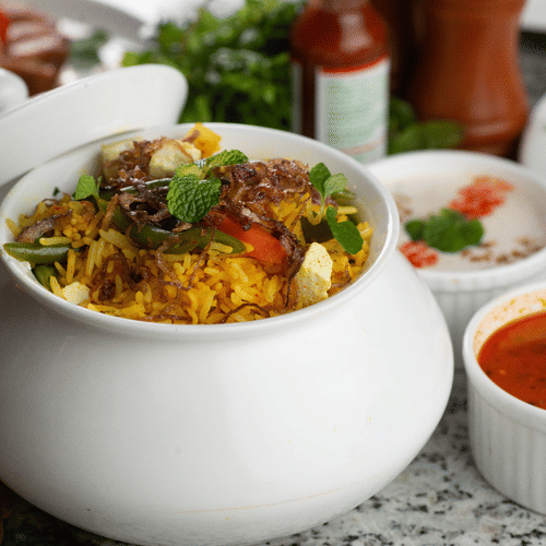 A glass desk in a room with a lamp, books, and a chair at Polo Hotel Agartala