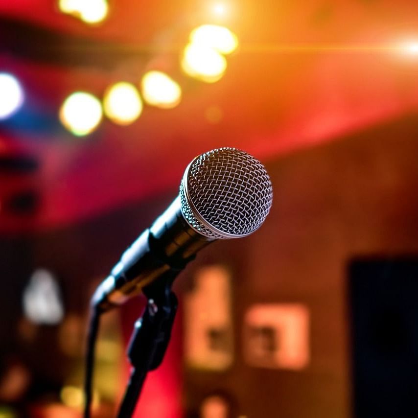 a close up image of a microphone mounted on a stand with warm lights in the background