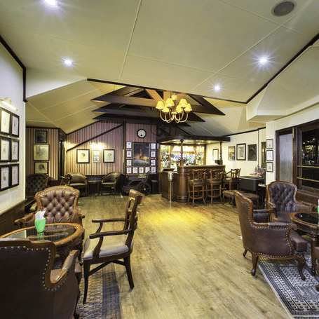 Relaxed hotel bar or sitting room with a collection of dark leather armchairs and soft, ambient lighting