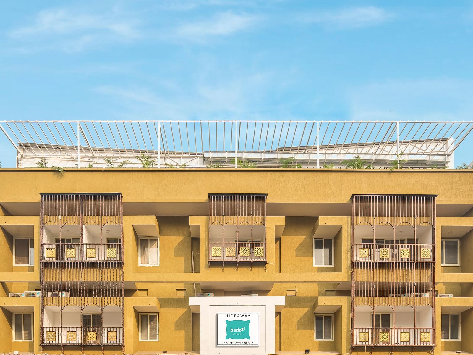 A close image of the front view of Bedzzz Varanasi, captured in daylight, featuring the logo of the property and the roof top area.