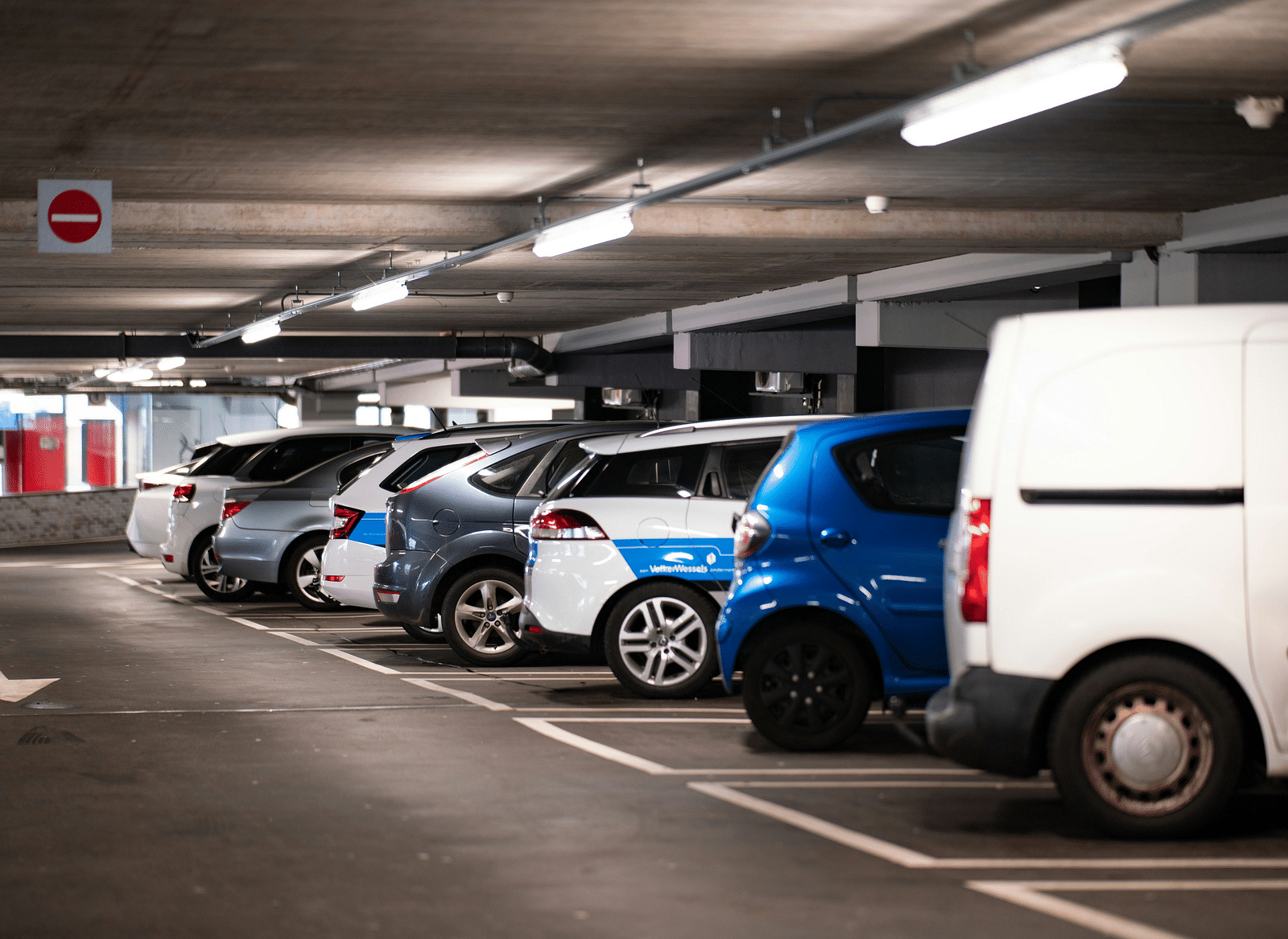 An indoor parking garage with multiple parked cars in a row.