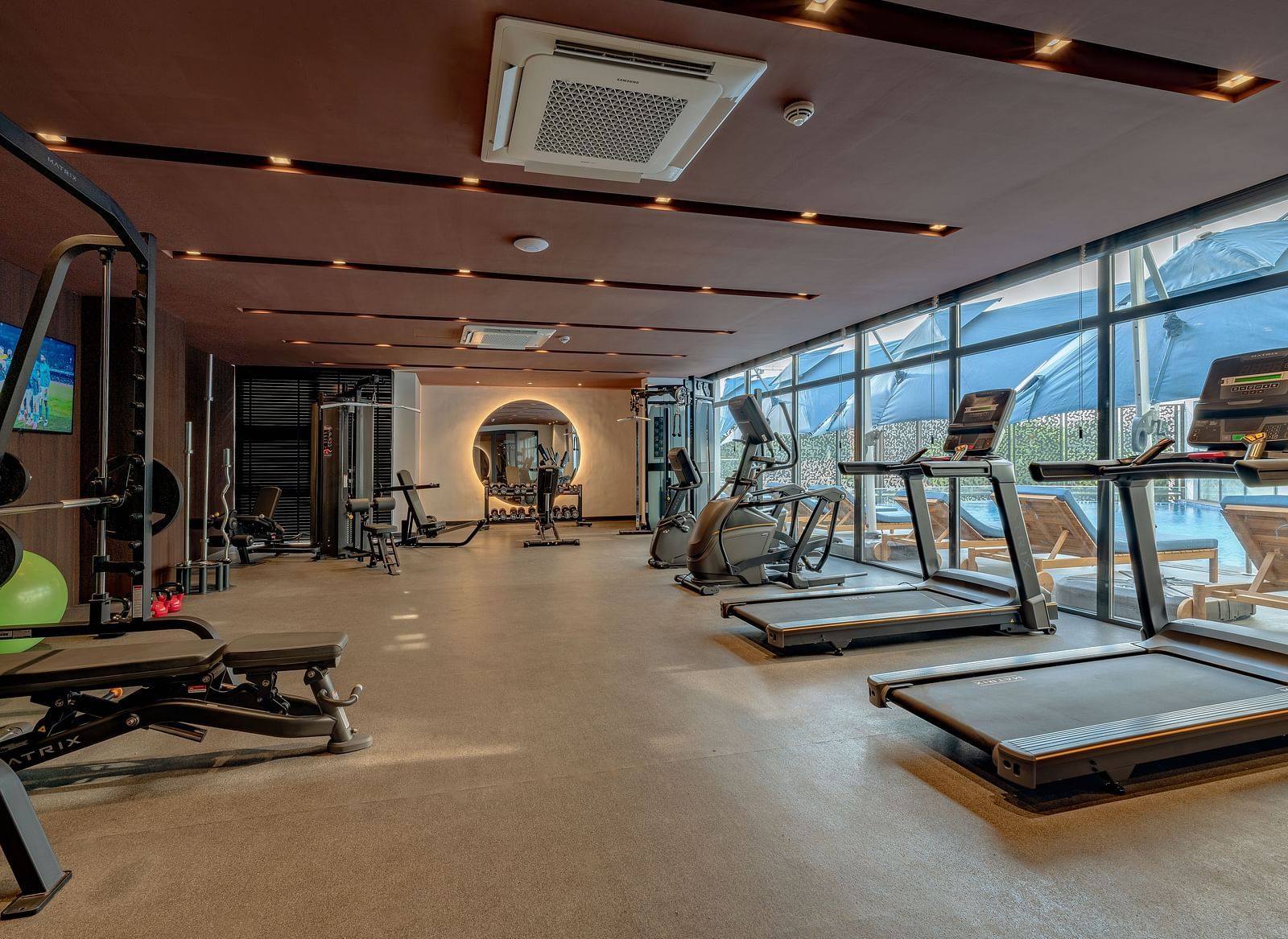 Bright, spacious gym with treadmills and weight machines lining the window wall. - The Pelican Hotel, Accra