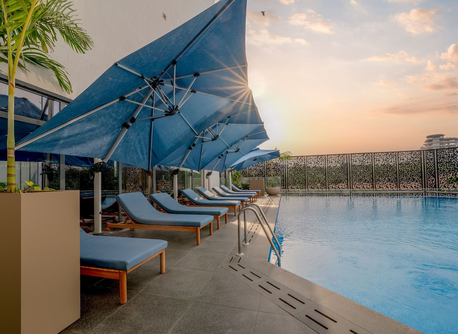 A pristine swimming pool glistens under a warm sunset sky, inviting a refreshing dip. - The Pelican Hotel, Accra