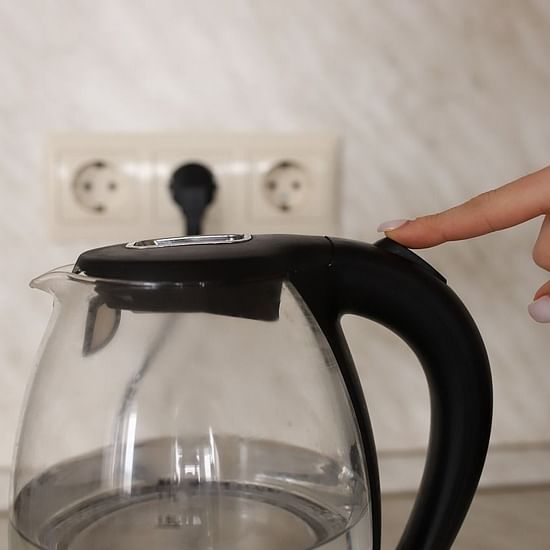 A person turning on an electric kettle