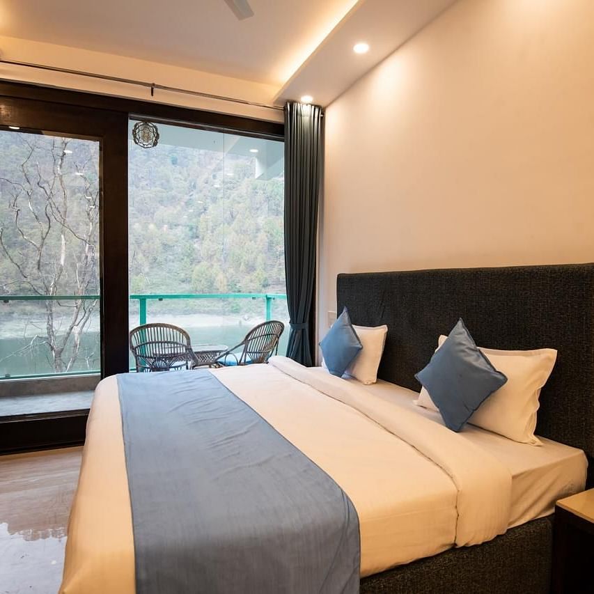 A compact bedroom with a bed placed against the wall, a ceiling fan, and a view through large windows.