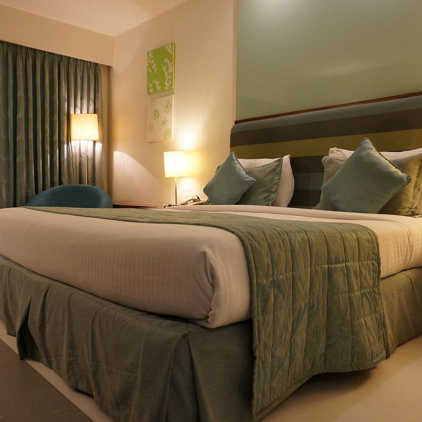 Corner view image of a double bed taken from a lower angle with warm lights in the room at Eminence The Corbett