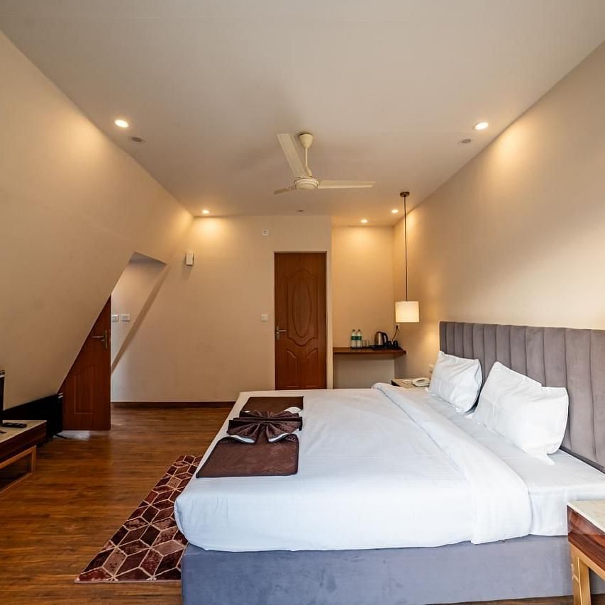 A hotel bedroom with a large white bed, a TV, and a ceiling fan