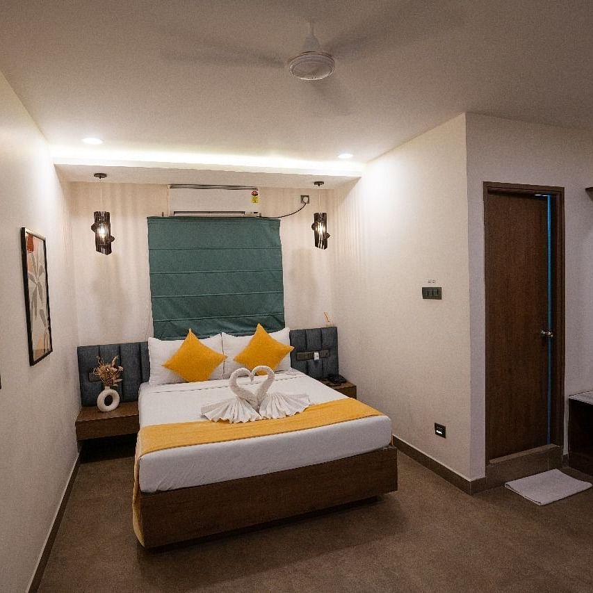 A room with a double bed, decorative pillows, wall art, and warm lighting, offering a welcoming atmosphere at Hotel Kyzen Smartstays – Smart, Reliable, Kyzen
