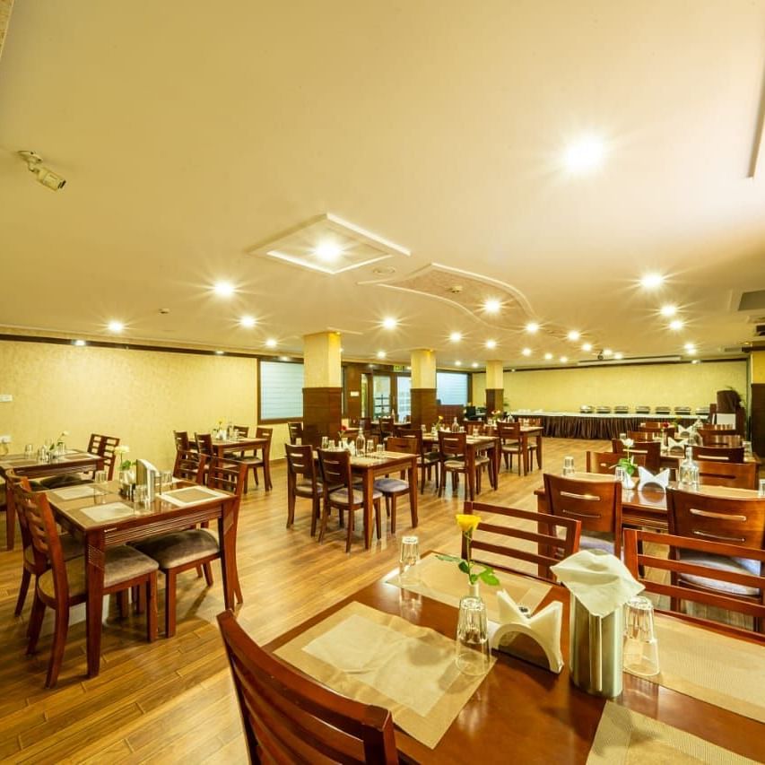 A spacious dining area with wooden furniture and warm lighting creates an inviting atmosphere at Lords Midtown Suites.