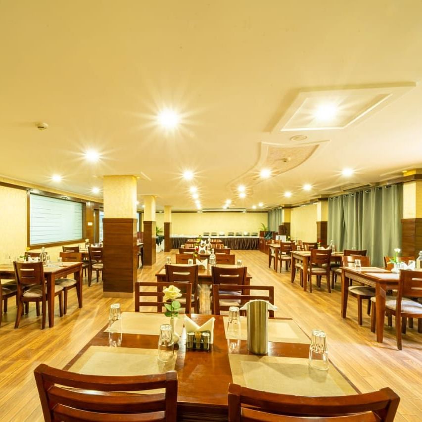 A well lit dining hall with wooden tables and chairs awaits guests, ready for meals at Lords Midtown Suites.