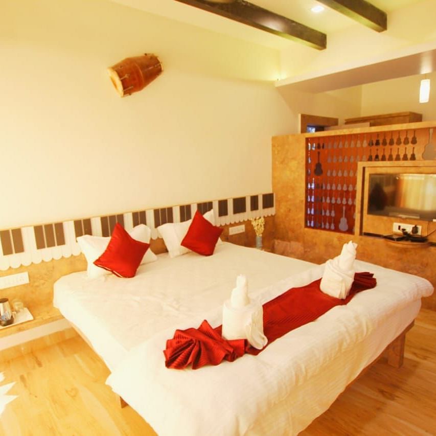 A diagonal view of the room featuring a spacious bed with towels folded in different shapes on it. There is a wooden table with a wall-mounted television at SeaFort Beach Resort