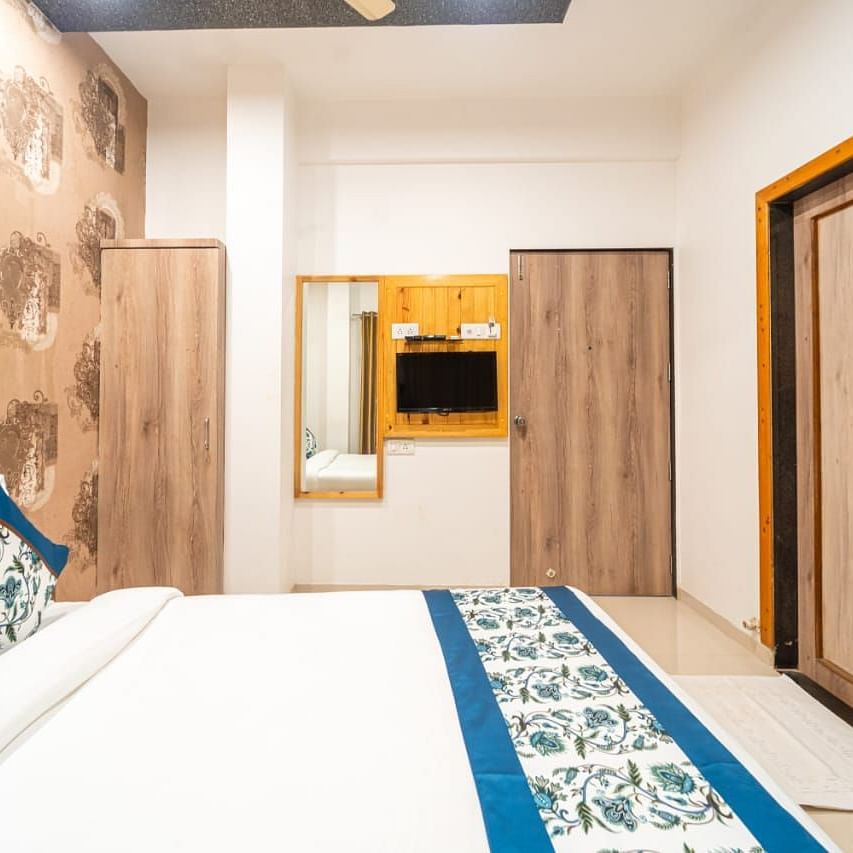 Standard Room highlighting the bed, patterned wall, a mirror, and a partially visible doorway