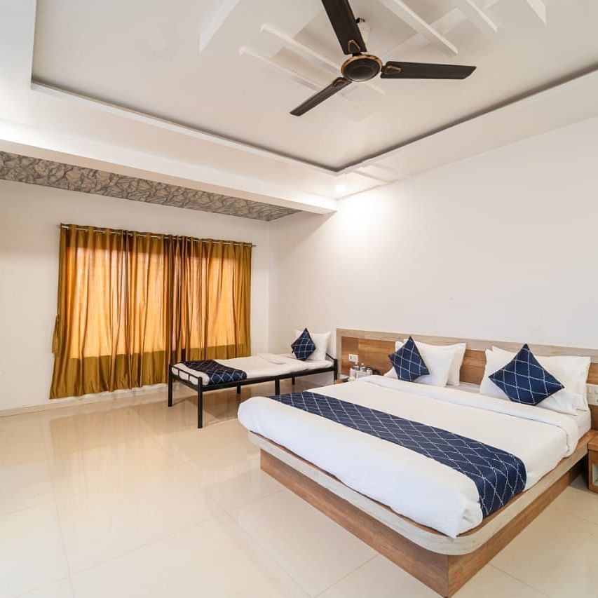Penthouse Suite with Balcony featuring a king size bed with white linens and a gray accent runner, two blue decorative pillows, bedside tables, a mattress, and a ceiling fan.