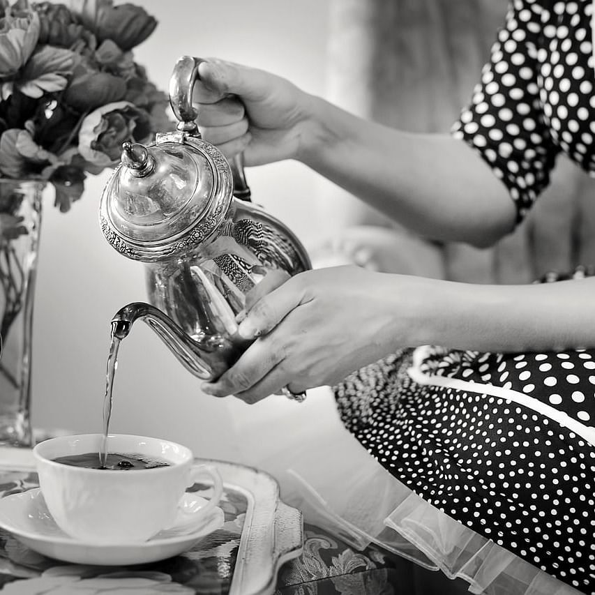 A women pouring tea into a cup.