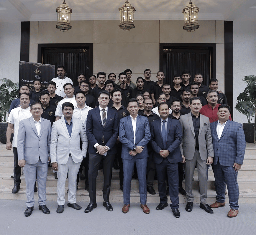 A group of people dressed in business formals gathered together in front of a hotel building.