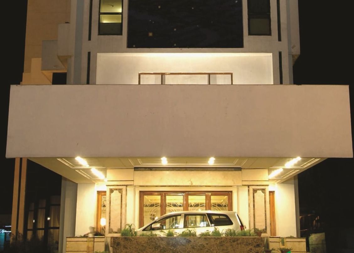 The facade view of a modern hotel building illuminated with lights in the ground floor  at night time.