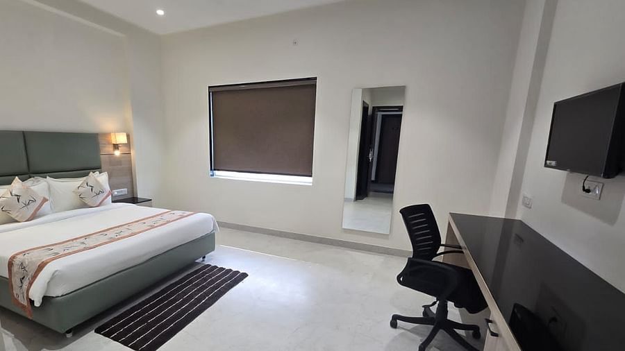 Deluxe room in Clarks Inn Express, Firozabad, featuring a neatly made king size bed, work desk and a wall mounted TV.