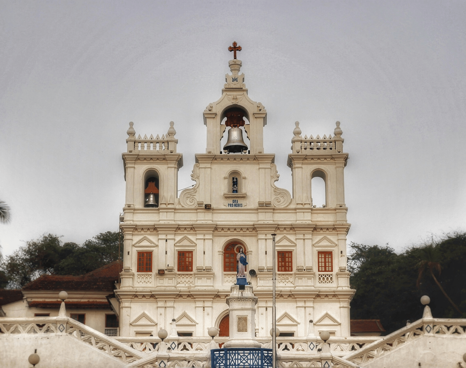 A historic white church in Goa featuring a bell at the top.