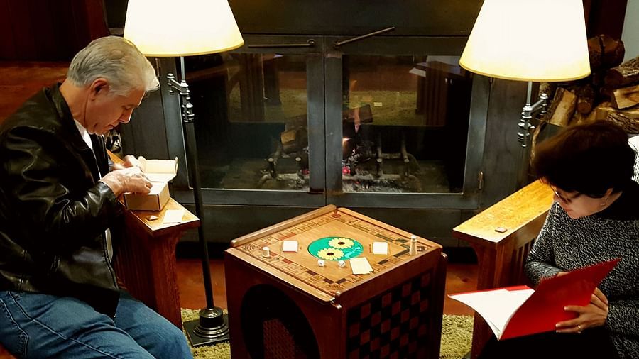 Two people sitting by a fireplace, playing a board game with a cozy ambiance - Brewery Gulch Inn & Spa