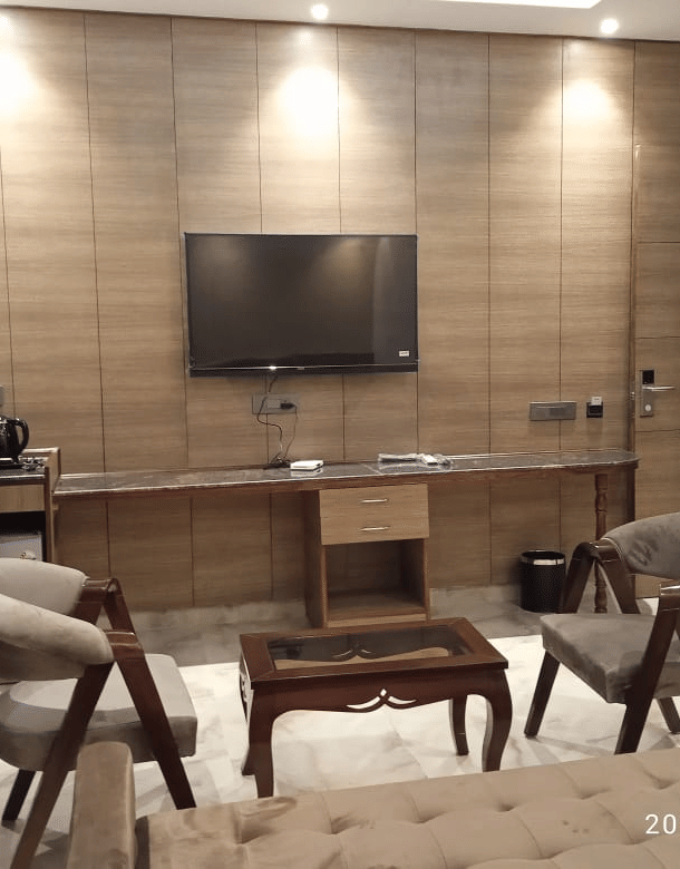 Executive Suite sitting area with a wall-mounted TV, armchairs and a carved table, Lime Tree Hotel Near India Expo Mart