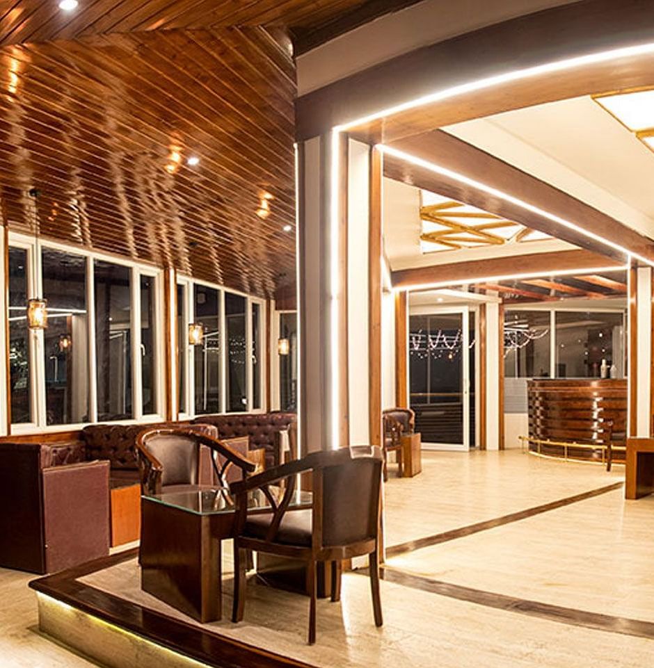a wide angle shot of a bar featuring leather couches, lit by warm lighting - Summit North Star, Gangtok