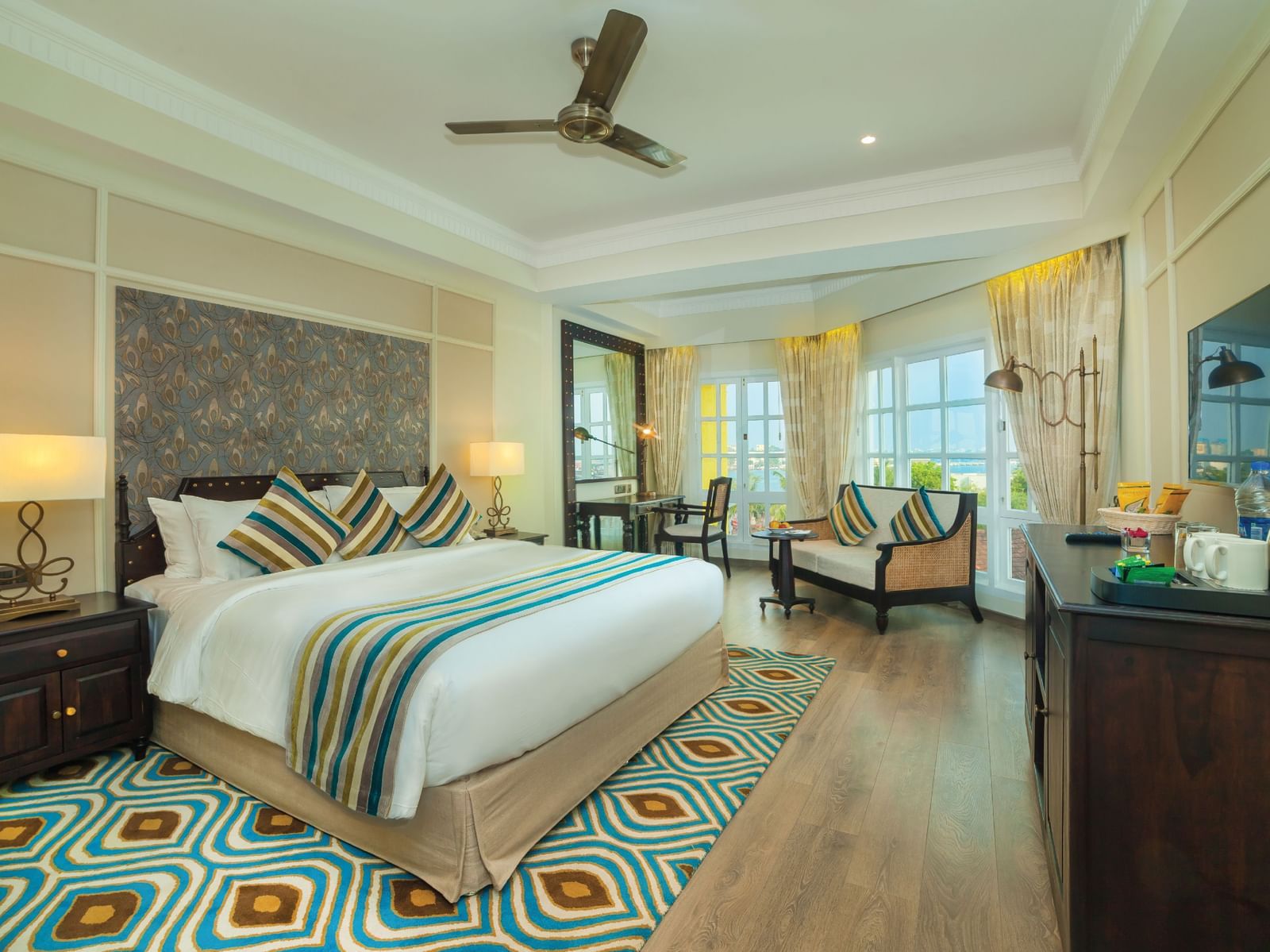 Spacious room with a large bed neatly arranged with cushions and blankets, surrounded by wooden furniture