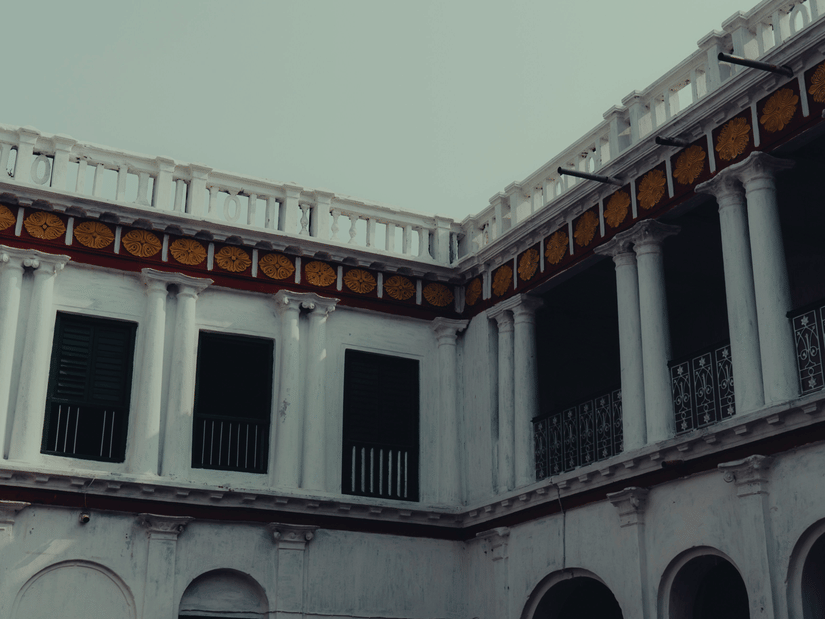 A classic white colonnaded courtyard balcony displaying colonial architectural influences beneath an overcast sky