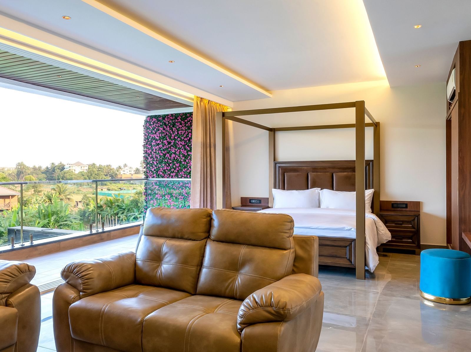 A double bed with wooden beams with a sofa in front of it inside one of the rooms - The Tanisi Hotels & Resorts, Goa