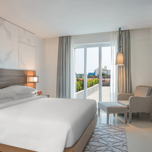 King Room with a balcony decked with a plush bed, couch and television at The Residency Towers Rameswaram