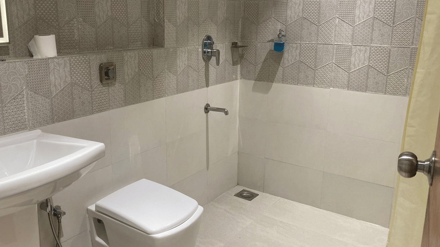 Contemporary bathroom featuring white porcelain fixtures and textured grey wall tiling - DAN Resorts & Weddings, Palghar