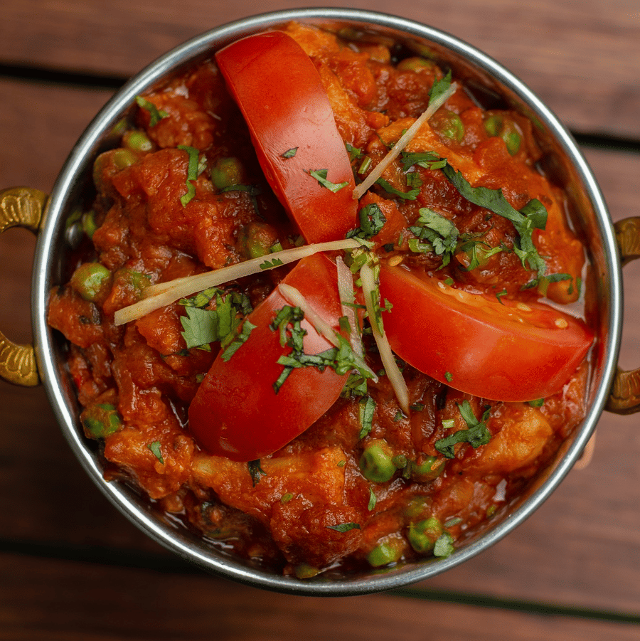 Semi- gravy served on the kadai and garnished with tomato and coriander  on top.